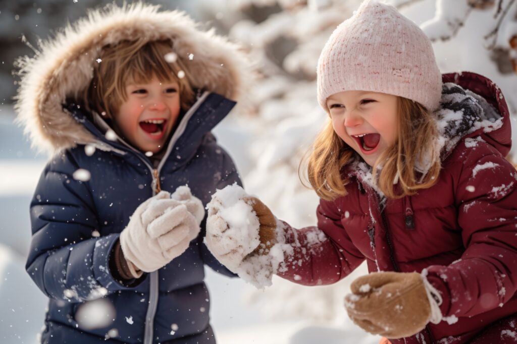 Un bambino e una bambina giocano con la neve in piumini per bambini.