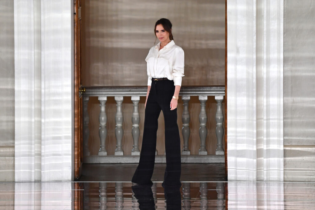 Victoria Beckham indossa una camicia bianca e pantaloni neri a vita alta