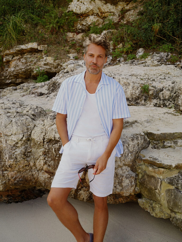 uomo in spiaggia con pantaloncini di lino e camicia a maniche corte